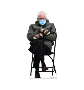 Man sitting on a chair, wearing mittens.