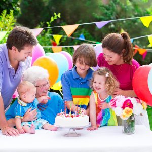 Family celebrates birthday with cake and balloons.