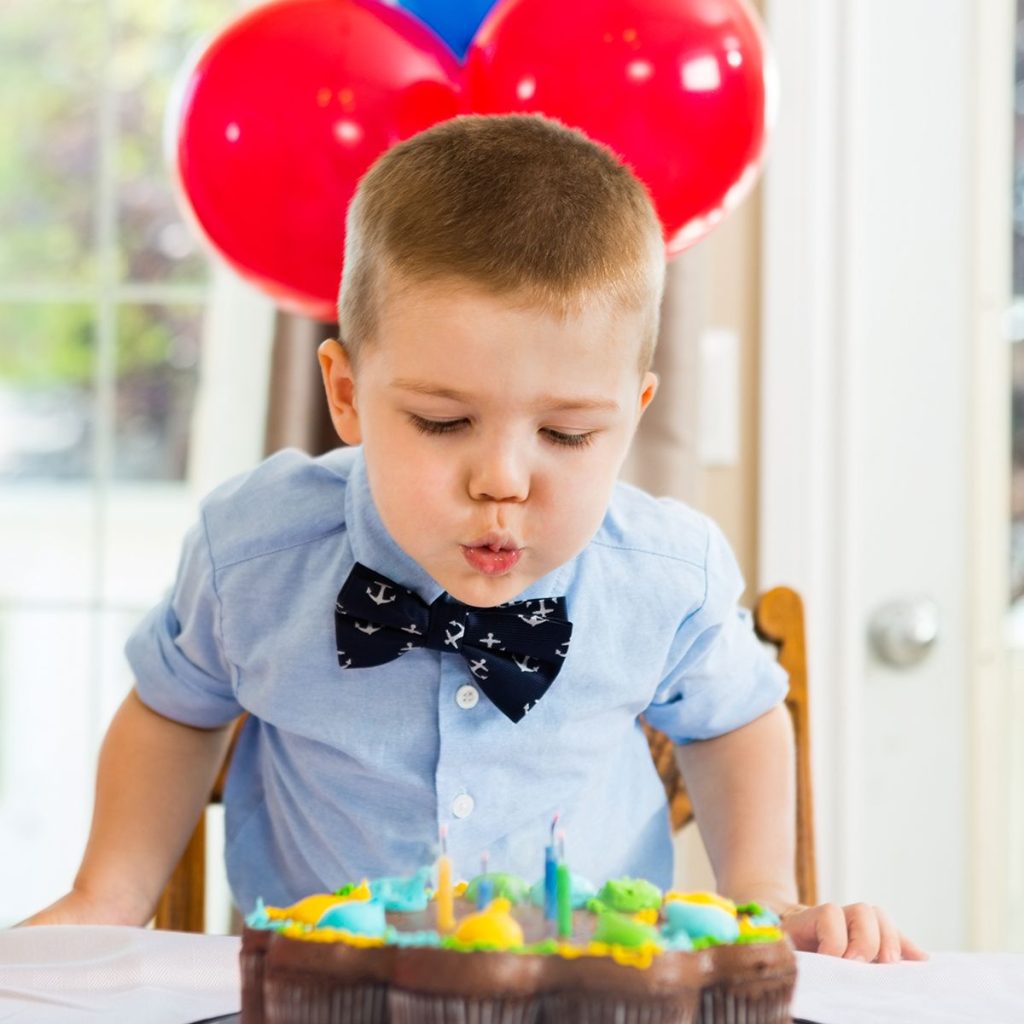 Boy blowing candles on birthday cake.