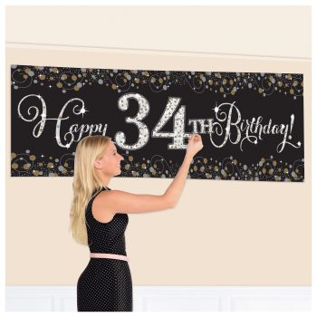 Woman decorating "Happy 34th Birthday" banner.