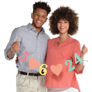 A smiling couple holding colorful anniversary numbers 5, 6, and 24.