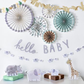 Decorative baby shower setup with pastel paper fans and animal figurines.