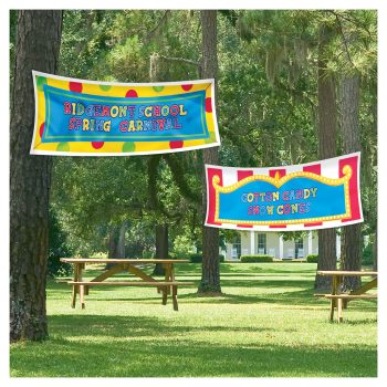 Colorful banners hang between trees at a picnic area in a park.