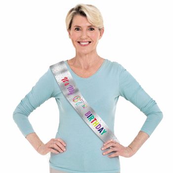 Woman wearing birthday sash, smiling confidently.
