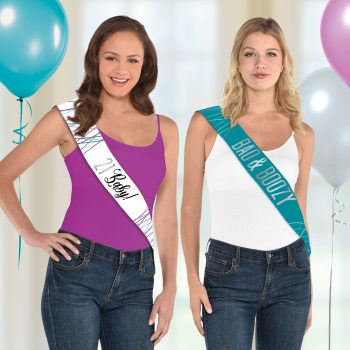 Two women wearing colorful sashes, smiling.