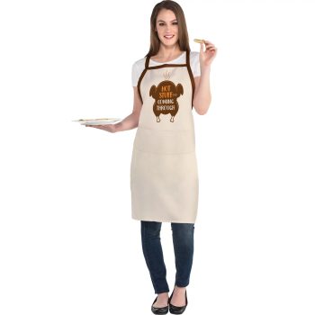 Woman wearing apron, holding plate and cookie.