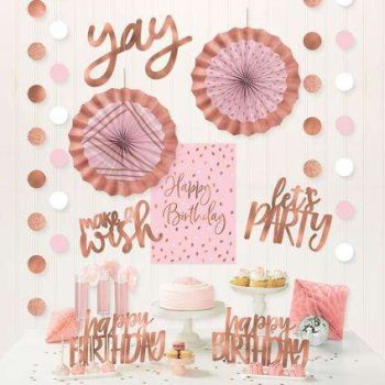 Rose gold and pink birthday party decorations with cupcakes and confetti.