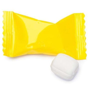 White mint candy next to a yellow wrapper.